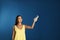 Young woman turning on air conditioner  blue background