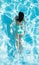 Young woman in turquoise bikini swimming under water in a swimming pool