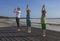 Young woman and two children practicing yoga on the beach.