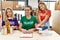 Young woman with two daughters wearing volunteer t shirt at donations stand looking positive and happy standing and smiling with a