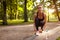 Young woman tying laces on her sneakers in summer park at sunset. Runner having rest. Sport concept.