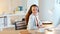 Young woman typing on computer and smiling in office using headset. Neat professional workspace indoors. Female could be