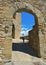 Young woman under Old stone arch gate and narrow street in the medieval village of Anghiari near city of Arezzo in Tuscany, Italy