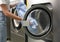 Young woman unloading washing machine in dry-cleaning