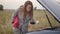 Young woman upset because of a car breakdown. The red-haired woman does not know the cause of the car breakdown. Car