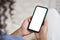 Young woman user holding smart phone mock up white screen in hands.