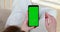 Young woman uses app touching green chromakey phone screen