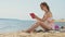 Young woman uses computer tablet on the beach, river bank