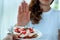 Young woman uses the hand to push the plate of pastry, refusing to eat flour and sugar, intended to lose weight