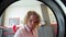 A young woman uses a tumble dryer for laundry in a laundry room