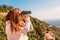 young woman using binoculars to spot birds in the sky, while hiking on top of mountain. person observing the horizon.