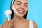 Young woman using facial brush on light blue background, closeup. Washing accessory