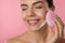 Young woman using facial cleansing brush on background, closeup. Washing accessory