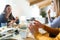 Young woman using her mobile phone while having lunch with friends at home.