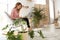 Young woman using  at home, space for text. Trendy room interior with plants