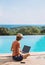 Young woman using laptop computer in hotel over sea background. Freelance work and travel concept.