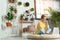 Young woman using laptop in room with home plants