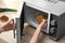 Young woman using microwave oven on table