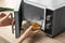 Young woman using microwave oven on table