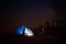 Young woman using phone on night camp on mountain trail.