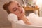 Young woman using pillow while enjoying bubble bath indoors