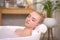 Young woman using pillow while enjoying bubble bath indoors