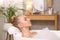 Young woman using pillow while enjoying bubble bath indoors