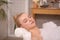 Young woman using pillow while enjoying bubble bath indoors