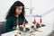 Young woman using professional overlock sewing machine in workshop studio. Equipment for edging, hemming or seaming