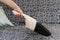 Young woman using a small manual vacuum cleaner while cleaning textile upholstery on the couch