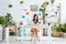 Young woman using smartphone while sitting in spacious room with green plants and paintings on wall