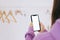 Young woman in using smartphone with white screen mock-up in white wardrobe room with floor rack