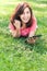 Young woman using tablet outdoor laying on grass, smiling.