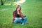 Young woman using tablet outdoor sitting on grass, smiling.