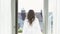 Young woman on vacation walking at the balcony in white bathrobe. Video. Rear view of a young brunette woman enjoying