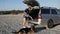 Young woman vacuuming car trunk using a vacuum cleaner removing dirt and dust from car trunk outdoors at sunset with her