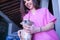 Young woman veterinarian in pink medical suit auscultating with a stethoscope a small dog who is very relaxed. Concept working