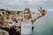 Young woman with victory gesture on beauty landscape of ocean rocky beach
