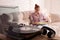 Young woman with vinyl discs in living room, focus on turntable