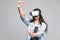 Young Woman with virtual reality goggles studio shot, gray background