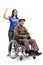 Young woman volunteer pushing a senior man in a wheelchair and showing thumbs up