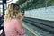 Young woman waiting on the train platform, tints her lips with lipstick