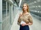 Young woman waiting for train at subway station, looking at paper