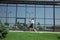 Young woman walking against glass` wall in airport, traveler with small baggage, influencer`s lifestyle