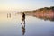 Young woman walking alone on beach at sunset with bare foot. Seminyak Beach, Bali, Indonesia