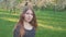 Young woman walking in an apple orchard in the spring flowers white. Portrait of a beautiful girl in the evening fruit