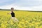 Young woman walking through a canola field. Freedom concept