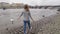 Young woman is walking on city embankment in Prague in cloudy spring day, watching white swans