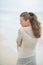 Young woman walking on cold beach. rear view