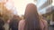 Young woman walking on crowded shopping street, touristic destination, back view